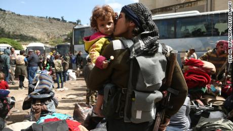 A rebel fighter from Eastern Ghouta kisses a child after arriving last week in Qalaat al-Madiq, Syria. 