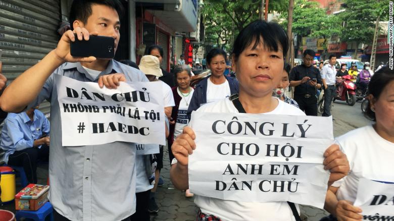 Protesters display placards as they march towards a courthouse during the trial of a prominent lawyer and five other activists in Hanoi on April 5.