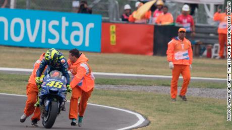 Valentino Rossi is helped back onto his bike after crashing out.