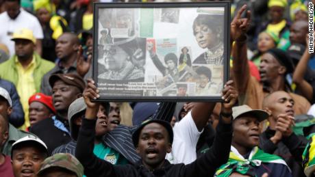 A man holds up a frame showing newspaper clippings of Madikizela-Mandela.