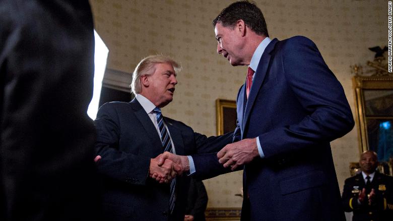 WASHINGTON, DC - JANUARY 22: U.S. President Donald Trump (C) shakes hands with James Comey, director of the Federal Bureau of Investigation (FBI), during an Inaugural Law Enforcement Officers and First Responders Reception in the Blue Room of the White House on January 22, 2017 in Washington, DC. Trump today mocked protesters who gathered for large demonstrations across the U.S. and the world on Saturday to signal discontent with his leadership, but later offered a more conciliatory tone, saying he recognized such marches as a &quot;hallmark of our democracy.&quot; (Photo by Andrew Harrer/Pool/Getty Images)