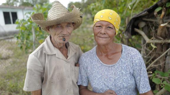 A couple in Céspedes, Cuba, pose in front of their home. After he took power in 1959, Fidel Castro promised to improve the lives of people living in Cuba's poverty-stricken countryside. He oversaw literacy and electrification campaigns and built hospitals for the rural poor. In recent decades, though, many Cubans living in the countryside have moved to cities, seeking better housing conditions and more economic opportunities.