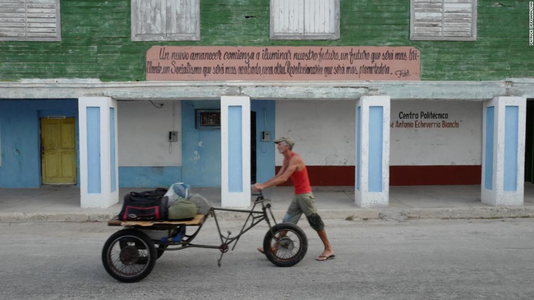 A Cuban man wheels his possessions in Gibara, Cuba, under a sign quoting Fidel Castro:  &quot;A new dawn shall begin to illuminate our future, a future that shall be more brilliant, a Socialism that shall be more refined, a Revolutionary work that will be more promising.&quot;