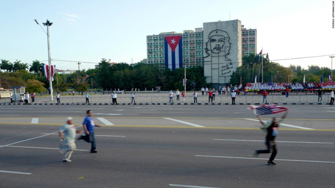 A protester carrying an American flag runs through Havana&#39;s revolution square on May Day 2017 ahead of a government-sponsored parade as plainclothes Cuban security agents try to catch him. International human rights groups criticize the Cuban government for repressing internal dissent. Cuban officials say the island&#39;s dissidents are &quot;mercenaries&quot; paid by Washington to stir up trouble.