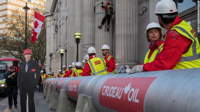 Greenpeace activists build an &quot;oil pipeline&quot; next to a cutout of  Canadian Prime Minister Justin Trudeau.