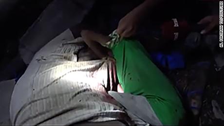 A young boy clings to his unconscious father&#39;s body after the airstrikes.