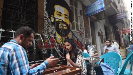 Egyptians gather at a café near a mural of Salah.