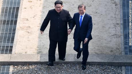 North Korean leader Kim Jong Un (L) and South Korean President Moon Jae-in hold hands as they cross the Military Demarcation Line at the DMZ on April 27.