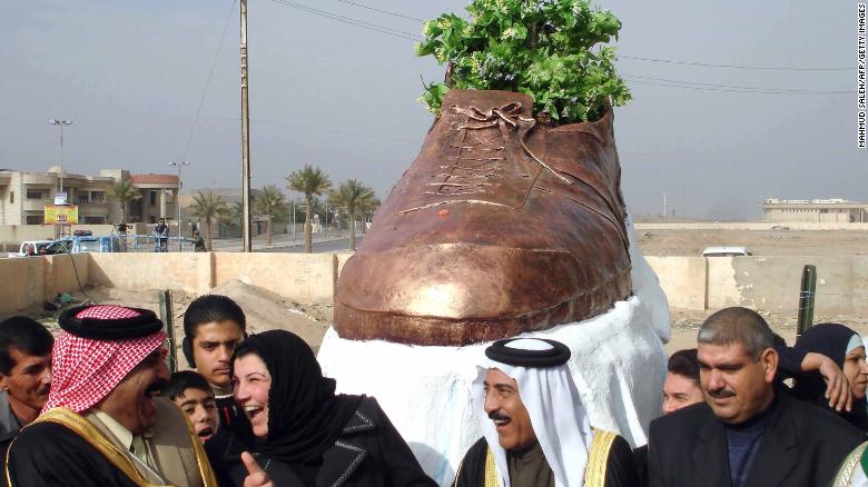 Iraqi officials share a laugh as they unveil a bronze shoe monument representing the one thrown by al-Zaidi at former US president George W. Bush.
