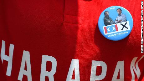 A supporter wears a badge with photographs of former Malaysian prime minister and opposition party Pakatan Harapan&#39;s prime ministerial candidate Mahathir Mohamad and jailed former opposition leader Anwar Ibrahim.