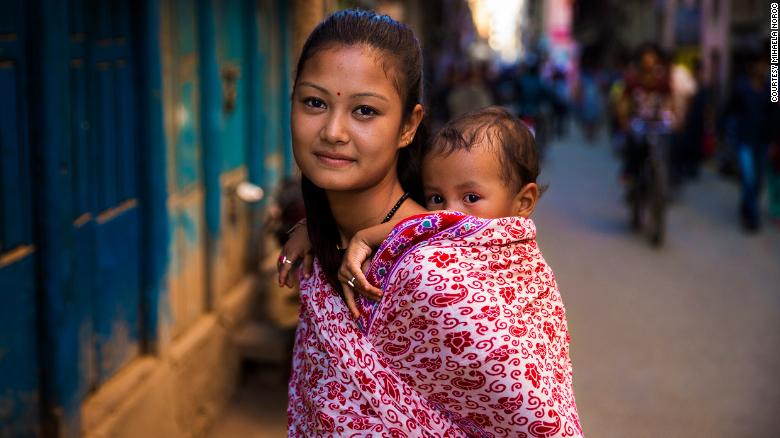 <strong>Kathmandu, Nepal:</strong> A Hindu mother carries her boy. "I remember that she was extremely tiny and had this baby face," said photographer Mihaela Noroc, recalling this older photo in a telephone interview from South Korea. "I asked if she was married, and she said yes. I think she was very young."”/></figure>



<p><a rel=