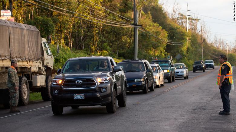 As authorities watch,  Leilani Estates residents line up on the road leading to the area.