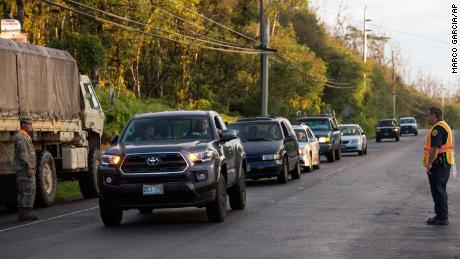 Under the watch of authorities, Leilani Estates residents line up Friday amid evacuation orders.