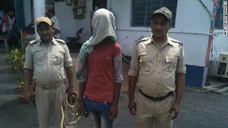 A suspect (C) being held by Indian police in the case of a 17-year-old girl who was raped and set on fire.