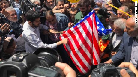 Protesters prepare to burn a US flag at a demonstration in Tehran.