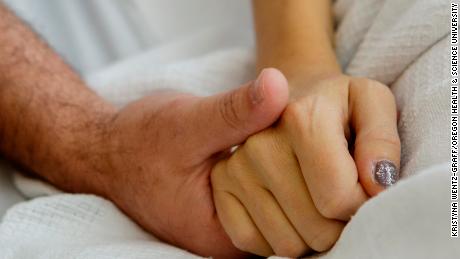 Erika Zak and her husband, Scott Powers, lock hands during a recent hospital visit. The two met 20 years ago. 