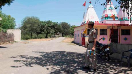 A police officer guards the main entrance to Rasana village. Local police have increased their presence in the village following the rape and murder of the Muslim girl.