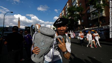 A Real Madrid football team fan holds a replica of the Champions League trophy.