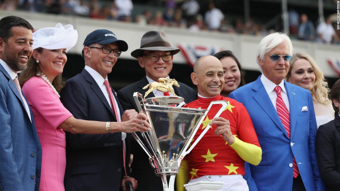 The team behind Justify poses with the new Triple Crown trophy after their horse won the Belmont Stakes and the Triple Crown on Saturday, June 9, in Elmont, New York.