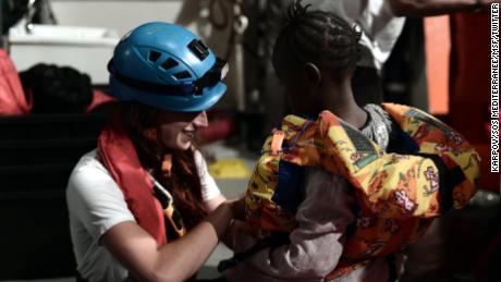 A rescue worker helps a young child on board the Aquarius.