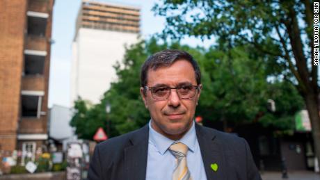 Survivor Miguel Alves wearing a commorative green heart in front of Grenfell Tower.