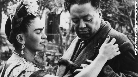 Frida Kahlo pets a monkey clinging to the jacket of her husband, Diego Rivera.