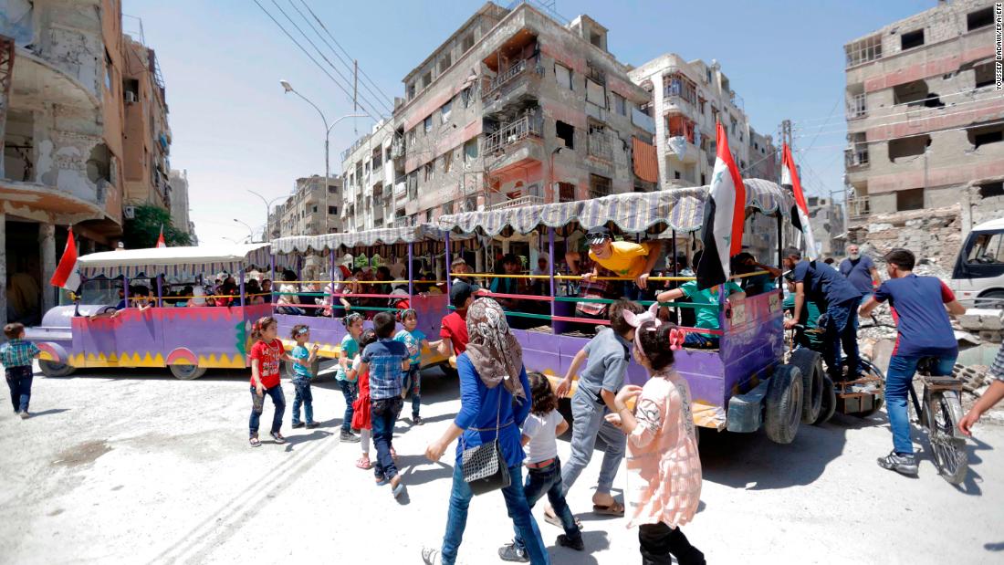 People ride a &quot;fun train&quot; on the war-damaged streets of Douma, Syria.