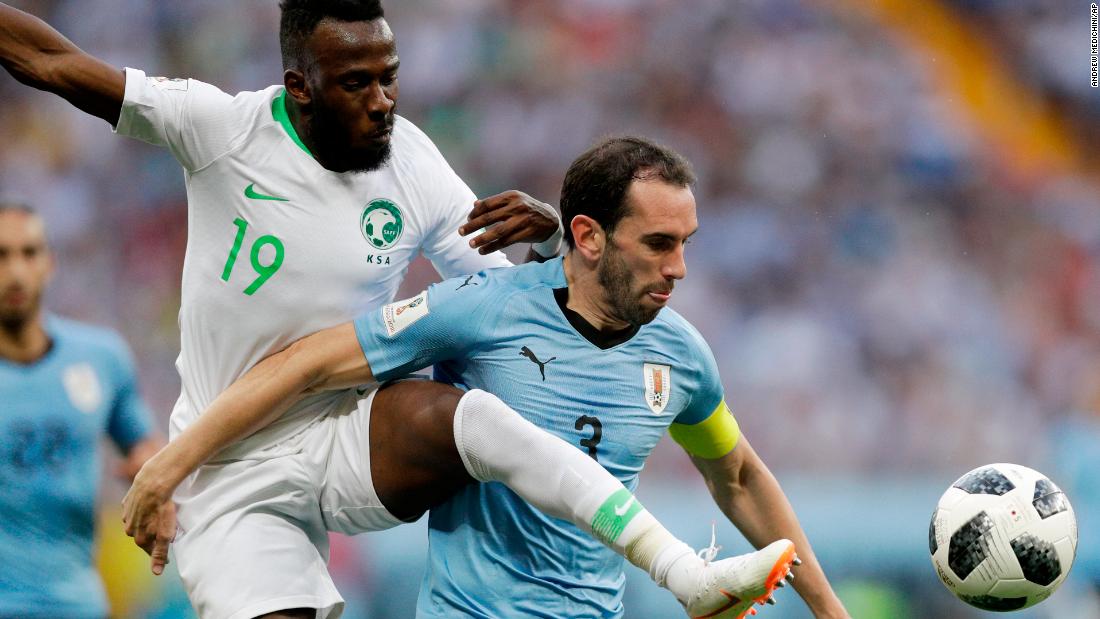 Saudi Arabia&#39;s Fahad Al-Muwallad, left, challenges Uruguay&#39;s Diego Godin.