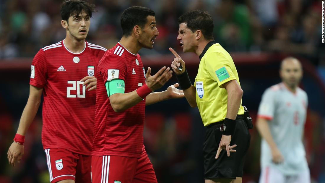 Referee Andres Cunha speaks with Iranian midfielder Ehsan Hajsafi during the match.