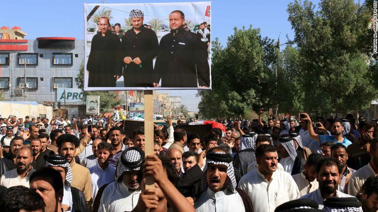 Iraqis carry a picture of some of the victims during a funeral procession in Karbala city Thursday.