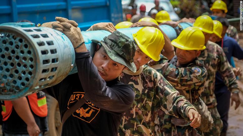 Rescue workers carry water pumping equipment into Tham Luang Nang Non cave on Sunday.