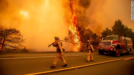 Firefighters try to stop a wildfire as wind drives embers across Highway 20 near Clearlake Oaks, Calif., on Sunday, July 1, 2018. (AP Photo/Noah Berger)