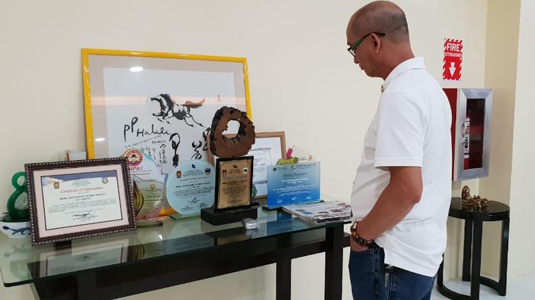 Mayor Halili&#39;s aide Carlos Mojares looks at his boss&#39; awards and trophies. He says Halili was incredibly proud of his collection.