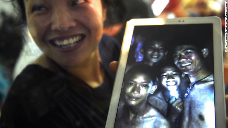 A family member shows a picture of four of the twelve missing boys near the Tham Luang cave at the Khun Nam Nang Non Forest Park in Mae Sai on July 2, 2018.
