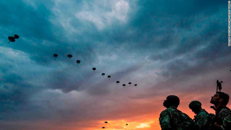 US Army soldiers look on while NATO paratroopers drop out of a US Air Force Hercules during the &#39;Swift Response 17&#39; joint airborn military exercise at Bezmer airfield near the village of Bezmer on July 18, 2017.