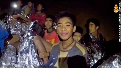 In this July 3, 2018, image taken from video provided by the Royal Thai Navy Facebook Page, Thai boys smile as Thai Navy SEAL medic help injured children inside a cave in Mae Sai, northern Thailand.  The Thai soccer teammates stranded more than a week in the partly flooded cave said they were healthy on a video released Wednesday, as heavy rains forecast for later this week could complicate plans to safely extract them. (Royal Thai Navy Facebook Page via AP)