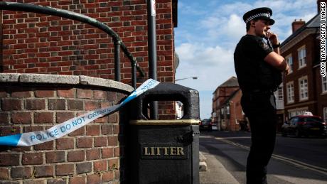 A police officer stands at a cordon around a public trash can Wednesday next to a supported housing project in Salisbury, thought to be connected to the Amesbury victims.