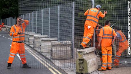 Workers install temporary security fencing outside Winfield House on Wednesday ahead of the visit of President Donald Trump.