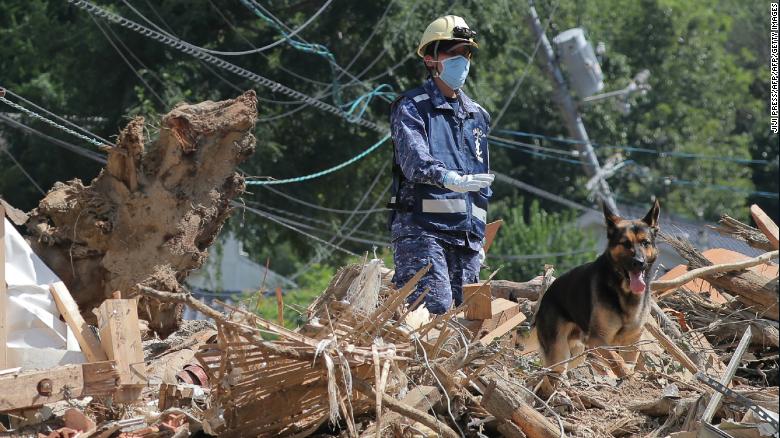 A member of Japan&#39;s Maritime Self Defense Forces searches for missing persons at a flood damage site in Kure, Hiroshima prefecture on Thursday.