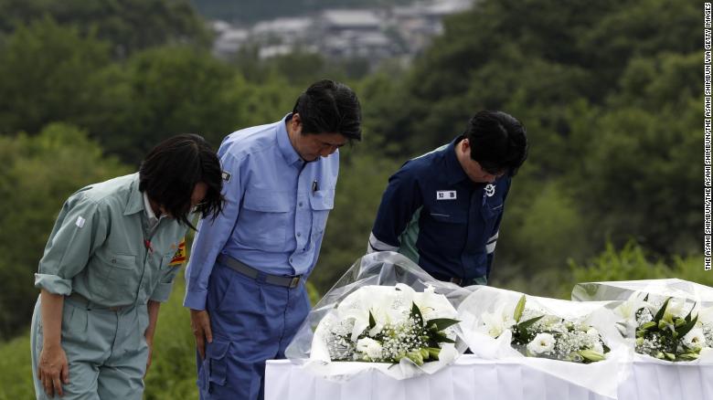 Prime Minister Shinzo Abe offer flowers at a hill he can see the submerged area on Wednesdayv in Kurashiki, Okayama, Japan.