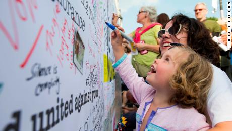 Anna Boyd watches as her daughter, Lyra, 3, adds her mark to the message wall.