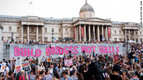 Crowds rally in Trafalgar Square, where a giant banner reads: &quot;Build bridges not walls.&quot;