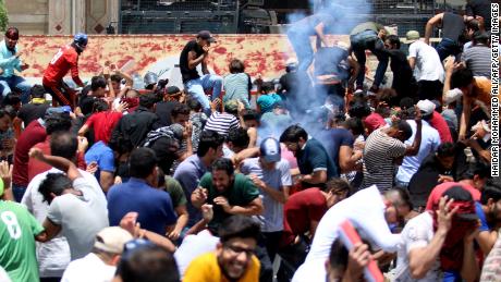Protesters react as Iraqi security forces fire tear gas during a demonstration against unemployment and a lack of basic services in the southern Iraqi city of Basra, on Sunday, July 15.