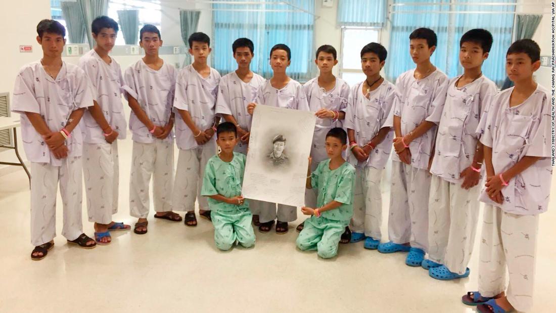 The team poses with a sketched portrait of Saman Kunan, a former Thai Navy SEAL who died on July 6 while returning from an operation to deliver oxygen tanks to the cave. He ran out of air while underwater, an official said.