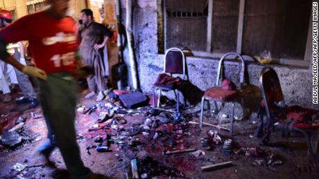 Pakistani security officials and volunteers search the site after a suicide bombing at an election rally in Peshawar on July 10, 2018.