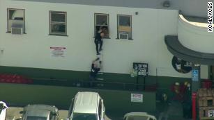 People crawl out of a back window at the Trader Joe&#39;s in Los Angeles.