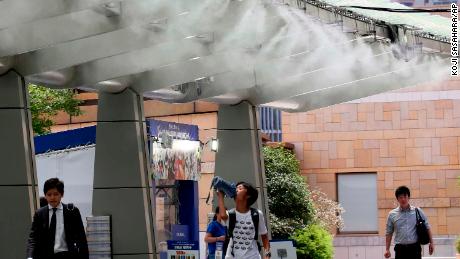 People cool down under the cooling mist spot in Tokyo on July 23. 