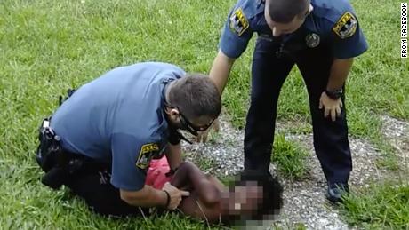 An image taken from a Facebook video shows two officers restraining a 10-year-old boy.