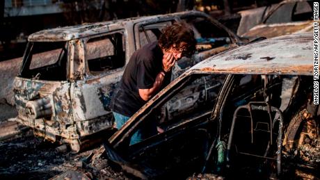 A woman searches for her dog Tuesday after the fire in Mati, near the Greek capital of Athens.