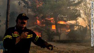 A firefighter reacts as a house burns during a wildfire in Kineta, near Athens.